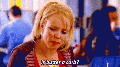 a woman is sitting at a table in a restaurant and asking is butter a carb .