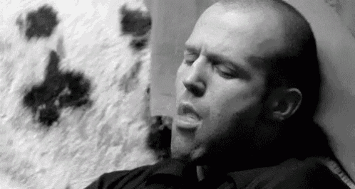 a man is sleeping in a chair with his eyes closed and his mouth open .