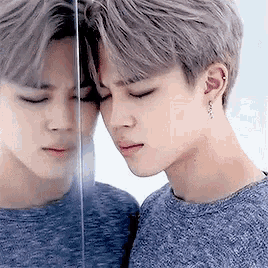 a young man is looking at himself in a mirror .