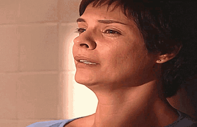 a close up of a woman 's face with a white tile wall in the background