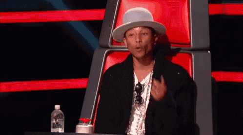 a man wearing a hat is sitting in a red chair giving a thumbs up .