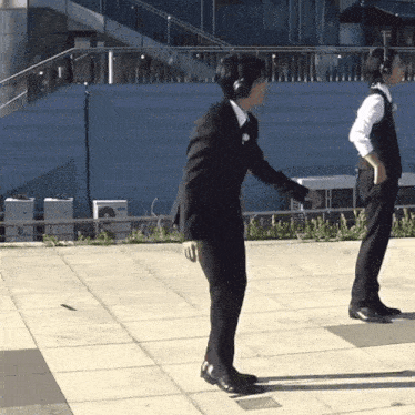 a man in a suit and headphones is standing on a sidewalk