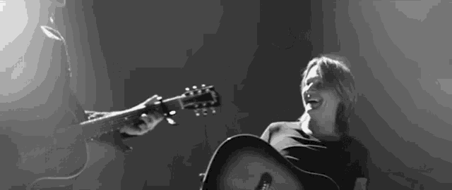 a black and white photo of a man playing a guitar and a woman holding a guitar