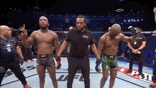 a referee stands between two fighters in a boxing ring