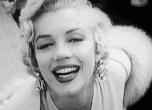 a black and white photo of marilyn monroe smiling with a fur collar .