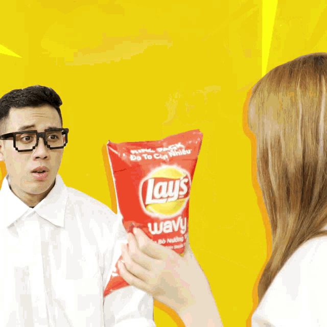 a man and a woman are holding a bag of lays chips