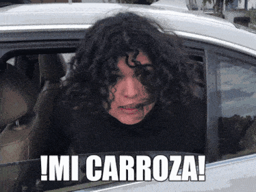 a woman with curly hair is sitting in a car with the words mi carroza written on the side