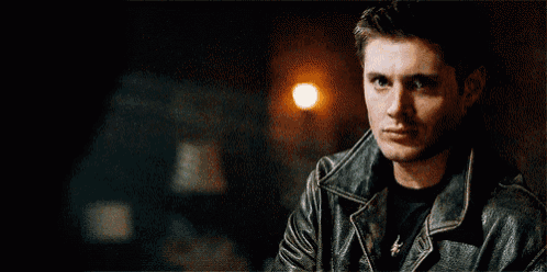 a man wearing a leather jacket is holding a lighter in his hand