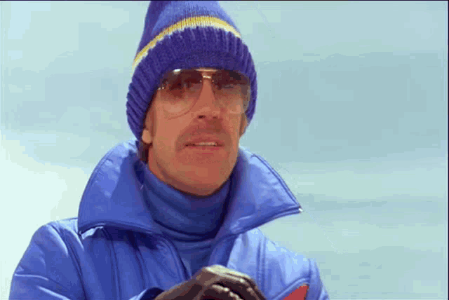 a man wearing a blue jacket and a blue hat and sunglasses