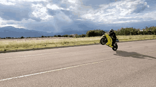a person is riding a yellow motorcycle down a road