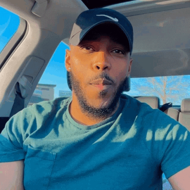 a man wearing a nike hat and a blue shirt looks at the camera