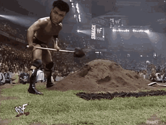 a wrestler is digging a hole with a shovel in front of a crowd at a smackdown event