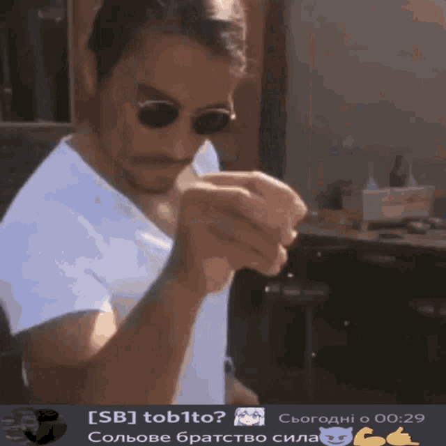 a man wearing sunglasses and a white shirt is holding something in his hands