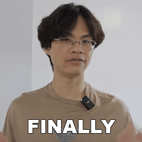 a man with glasses and a microphone around his neck has the word finally above him