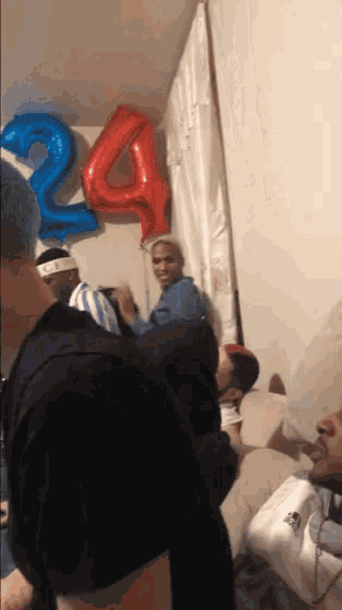 a group of people are gathered in a room with balloons that say 24