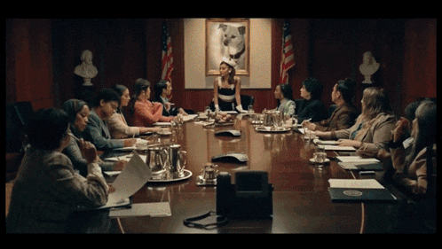 a group of people are sitting around a table with a picture of a dog on the wall behind them