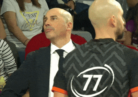 a man in a suit and tie stands next to another man in a 77 jersey