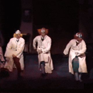 three men in white coats are dancing on stage