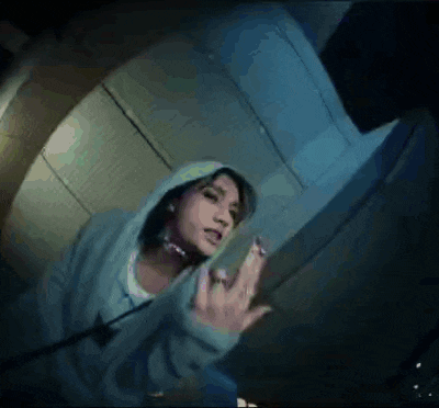 a woman in a hoodie is giving the middle finger in a video .