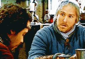 two men are sitting at a table talking and one has a beard