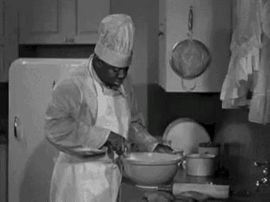 a black and white photo of a man in a chef 's hat preparing food .