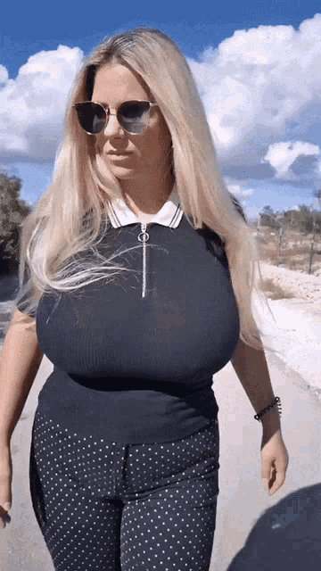 a woman wearing a black shirt and polka dot pants is walking down a road