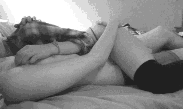 a black and white photo of a man and a woman laying on a bed .