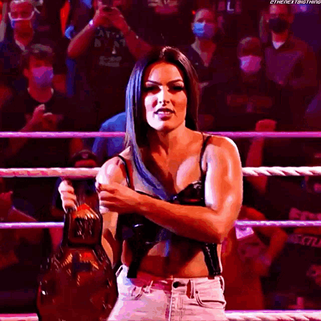 a woman is standing in a wrestling ring holding a championship belt