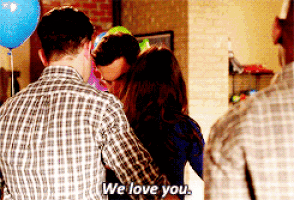 a man in a plaid shirt is hugging a woman in a room with balloons and says we love you