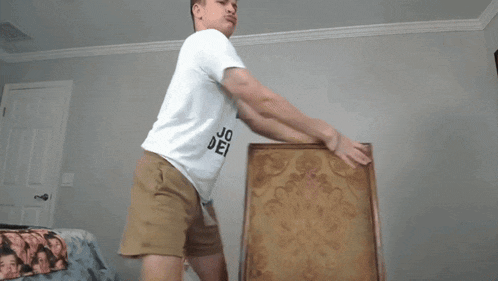 a man in a white t-shirt that says joe neal holds a picture frame