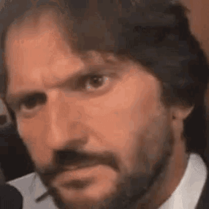 a man with a beard is making a funny face while smoking a cigarette .