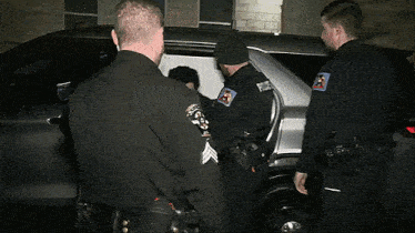 a man in a police k9 uniform is being escorted by other police officers