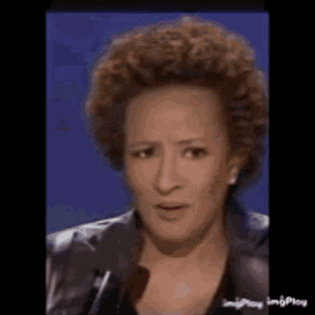 a woman with curly hair is talking into a microphone .