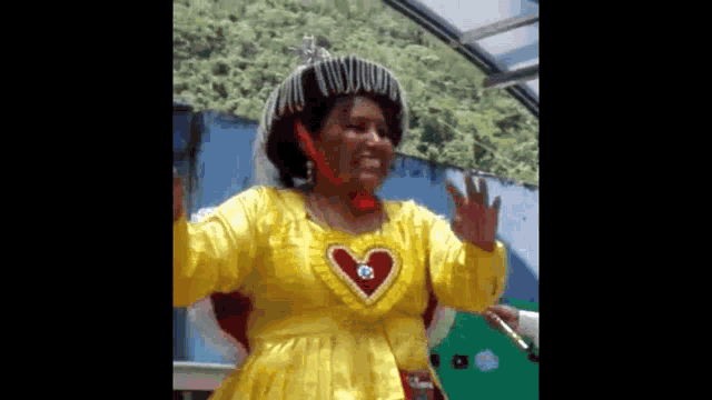 a woman is wearing a yellow dress with a heart on the chest