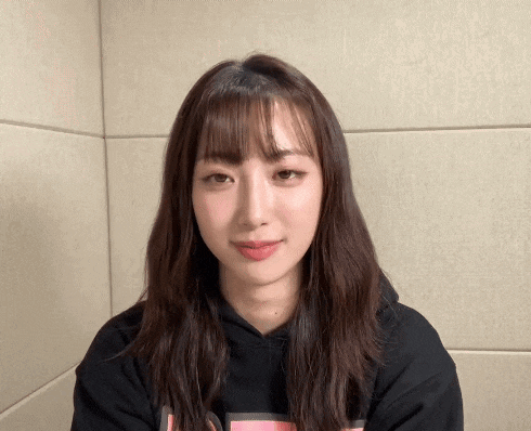 a woman with long hair and bangs wearing a black hoodie with the letter t on the front