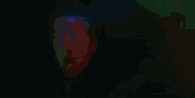 a green light is shining on a person 's face in a dark room