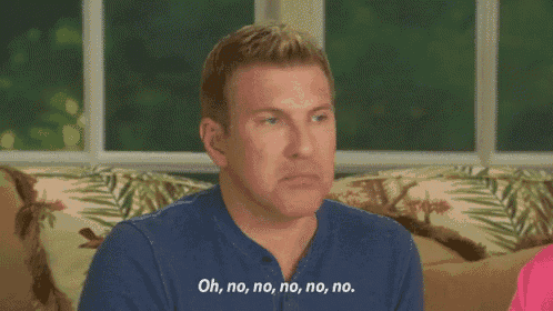 a man in a blue shirt is sitting on a couch and saying oh no no no no no