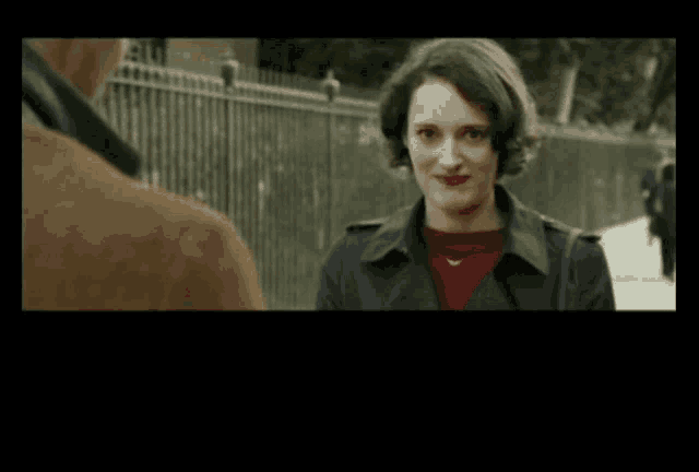 a woman in a trench coat is smiling while talking to a man