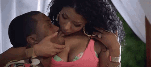 a man is touching a woman 's breast while she is wearing a pink tank top .