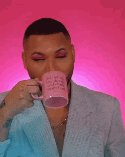 a man is drinking from a pink mug that says `` did i tell you how divinely and utterly happy i am ? ''