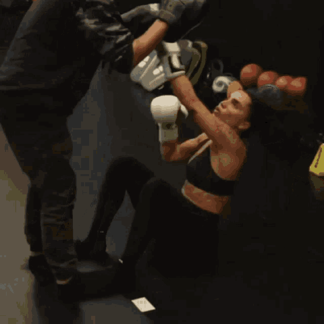 a woman wearing boxing gloves is being kicked in the face