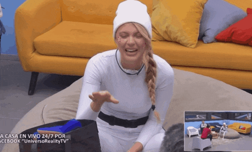 a woman in a white outfit is sitting in front of a yellow couch and a facebook advertisement