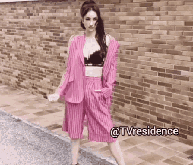 a woman in a pink suit is standing in front of a brick wall with the hashtag @tvresidence