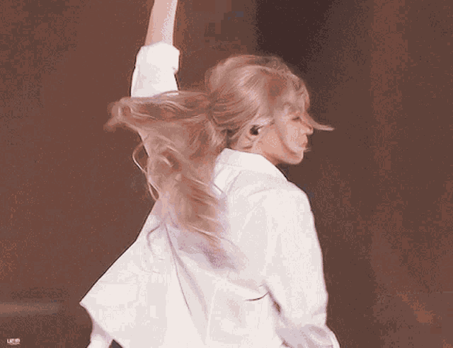 a woman in a white shirt is dancing on a stage .