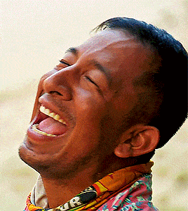 a man wearing a scarf with the letter r on it is laughing with his eyes closed