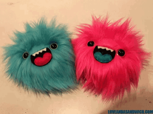 a blue and a pink stuffed animal are sitting next to each other on a table