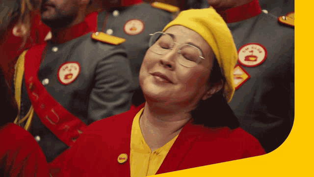 a woman wearing a yellow hat and a red jacket with a smiley face on it