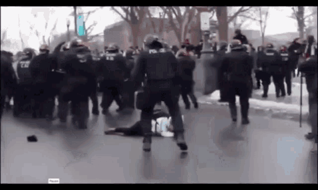 a group of police officers are fighting a group of protesters on the street .