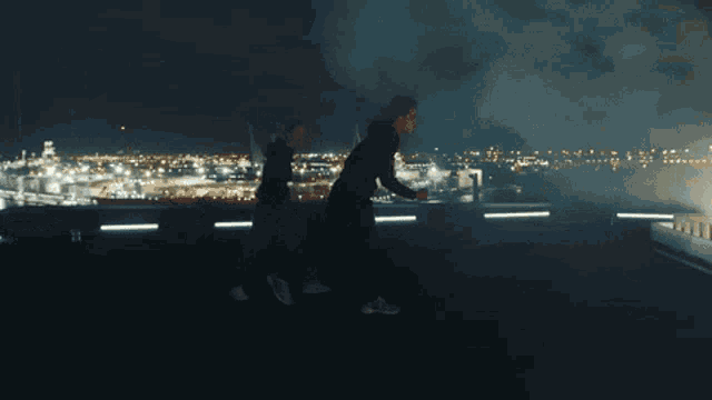 a man in a red shirt is running on a rooftop at night