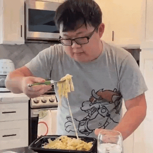 a man in a super mario shirt is eating pasta
